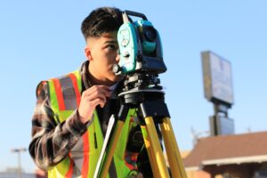 Young man looking though surveying equipment